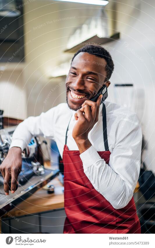 Happy barista on the phone in a coffee shop accessible human human being human beings humans person persons African black black ethnicity coloured 1