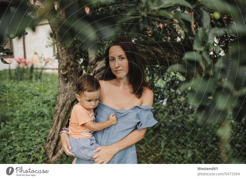 Portrait of mother holding baby in garden infants nurselings babies portrait portraits gardens domestic garden mommy mothers ma mummy mama people persons