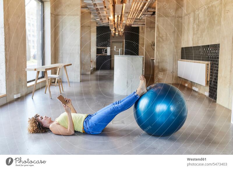 Woman with fitness ball lying on the floor using tablet in modern office Germany Fitness Ball Fitness Balls Balance Ball exercise ball Stability Ball Gym Ball