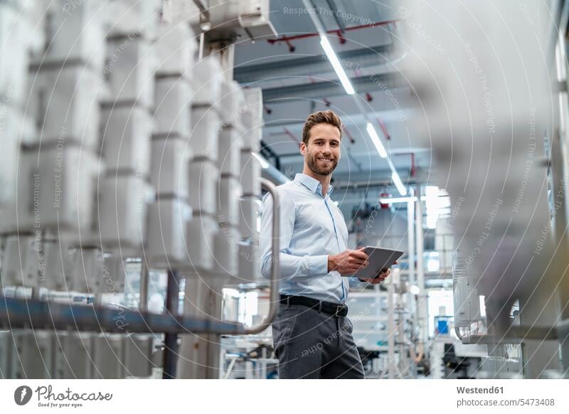 Portrait of a smiling businessman with tablet in a modern factory Occupation Work job jobs profession professional occupation business life business world