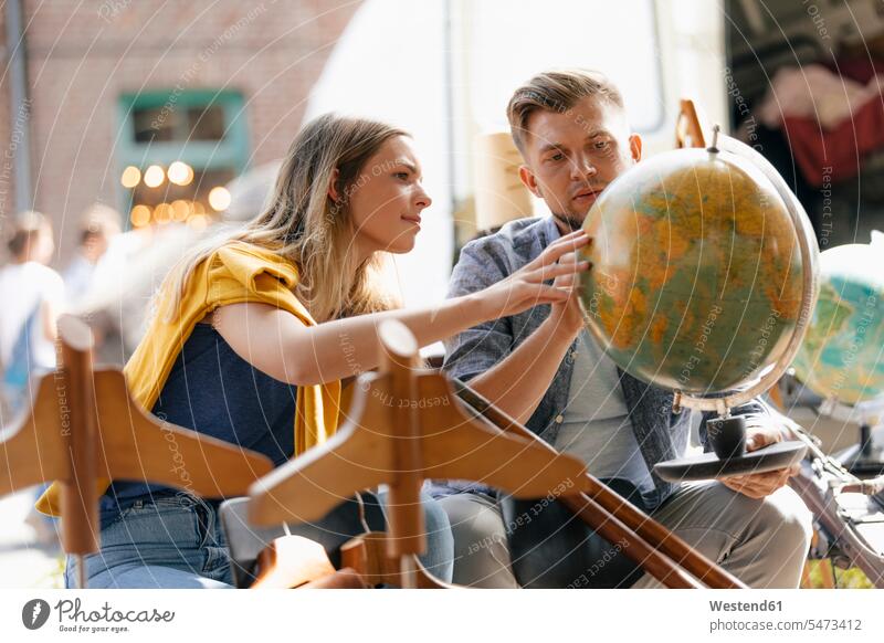 Belgium, Tongeren, young couple examining globe on an antique flea market globes examine antiques twosomes partnership couples looking view seeing viewing