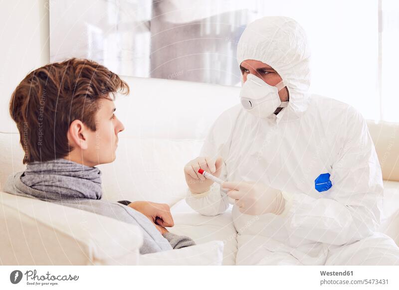 Doctor wearing protective suit explaining about medical test to patient at home color image colour image Germany indoors indoor shot indoor shots interior