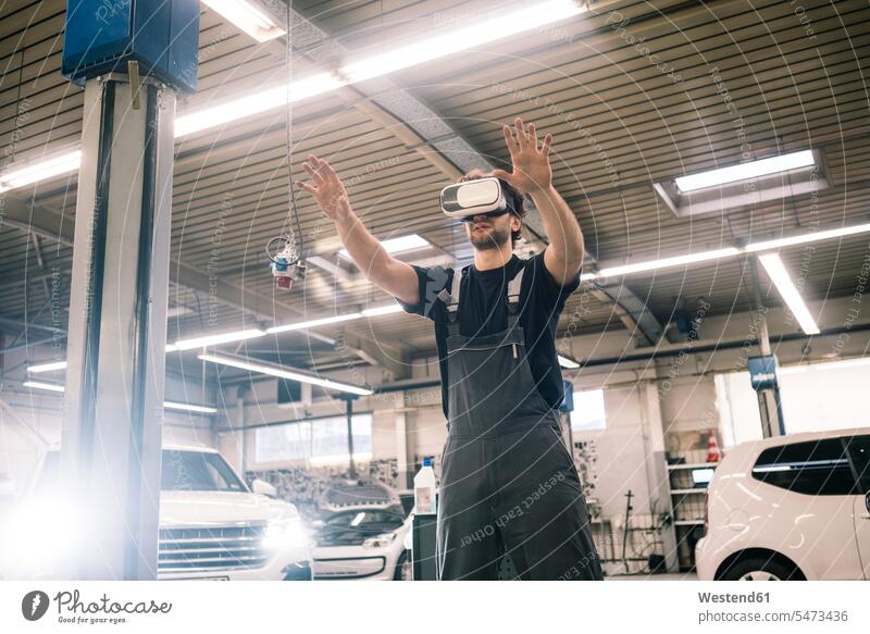 Car mechanic wearing VR glasses in a workshop Occupation Work job jobs profession professional occupation industrial industries machinist machinists mechanician