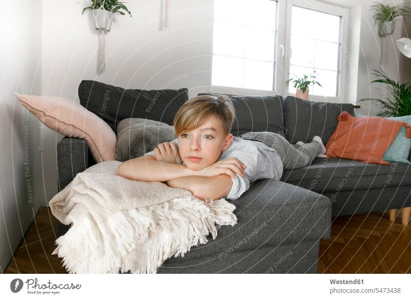 Teenage boy lying on couch, looking bored windows boring at home domestic room domestic rooms living rooms livingroom indoor indoor shot indoor shots interior