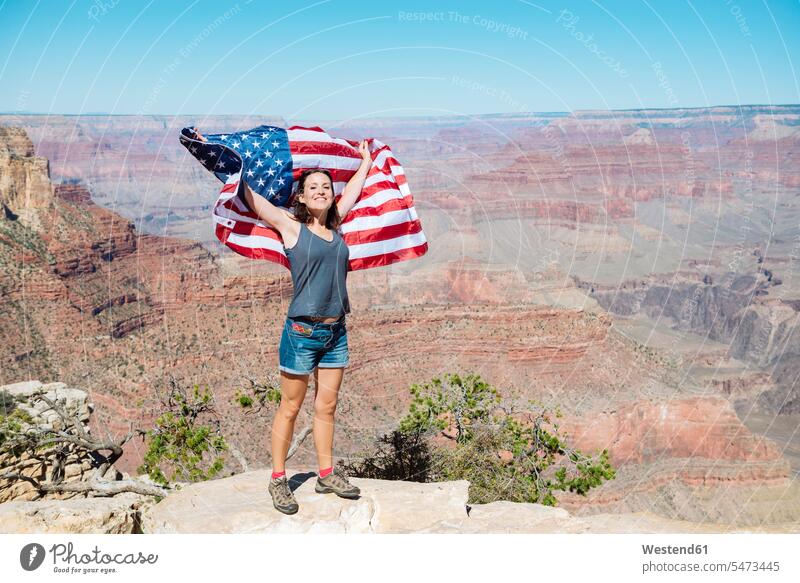 USA, Arizona, smiling woman with American flag at Grand Canyon National Park flags banner banners females women smile National Parks american ensign