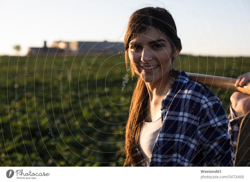 Young woman farmer with hoe on field portrait portraits Field Fields farmland females women farmhand Adults grown-ups grownups adult people persons human being