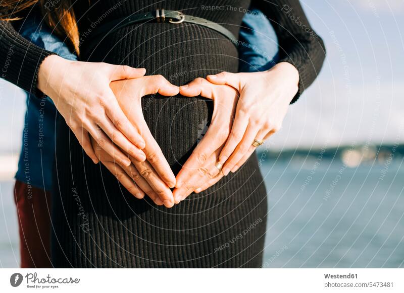Affectionate expectant parents shaping a heart with their hands on baby belly human human being human beings humans person persons caucasian appearance