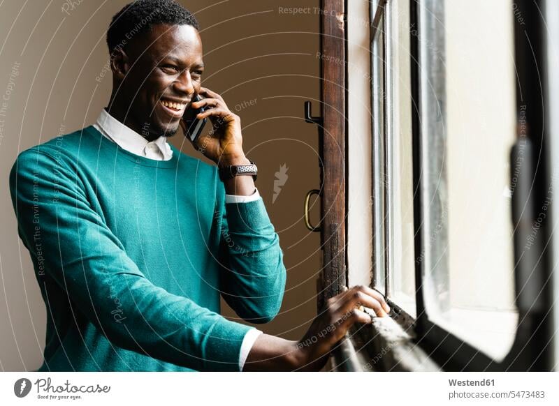 Happy man talking on the phone at the window business life business world business person businesspeople Business man Business men Businessmen windows jumper