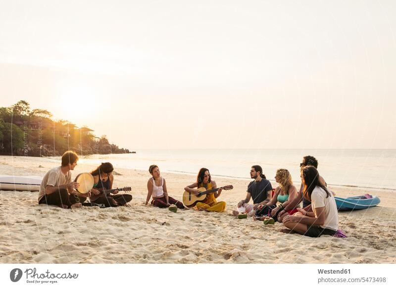 Thailand, Koh Phangan, group of people sitting on a beach with guitar at sunset guitars Seated Group groups of people beaches together stringed instrument
