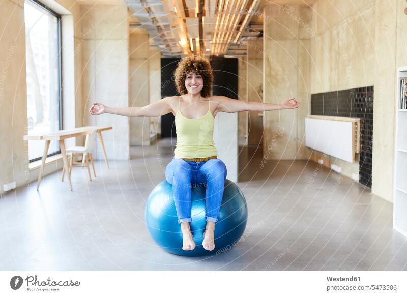 Portrait of smiling woman sitting on fitness ball in modern office front view frontal View From Front Frontal View front views head on head-on break room