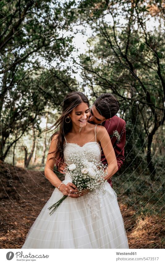 Groom kissing smiling bride in forest woods forests bridal couple bridal couples groom bridegrooms smile brides Wedding getting married marrying Marriage kisses