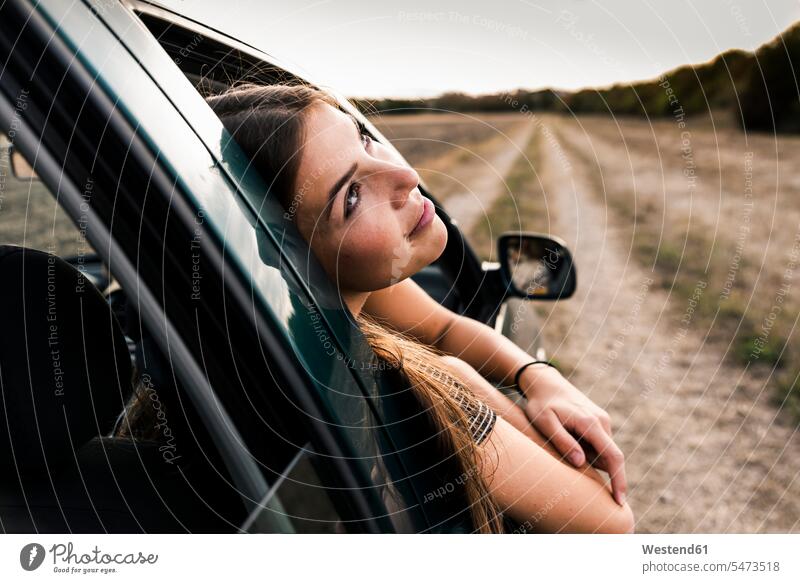 Smiling young woman leaning out of car window windows females women smiling smile automobile Auto cars motorcars Automobiles Adults grown-ups grownups adult
