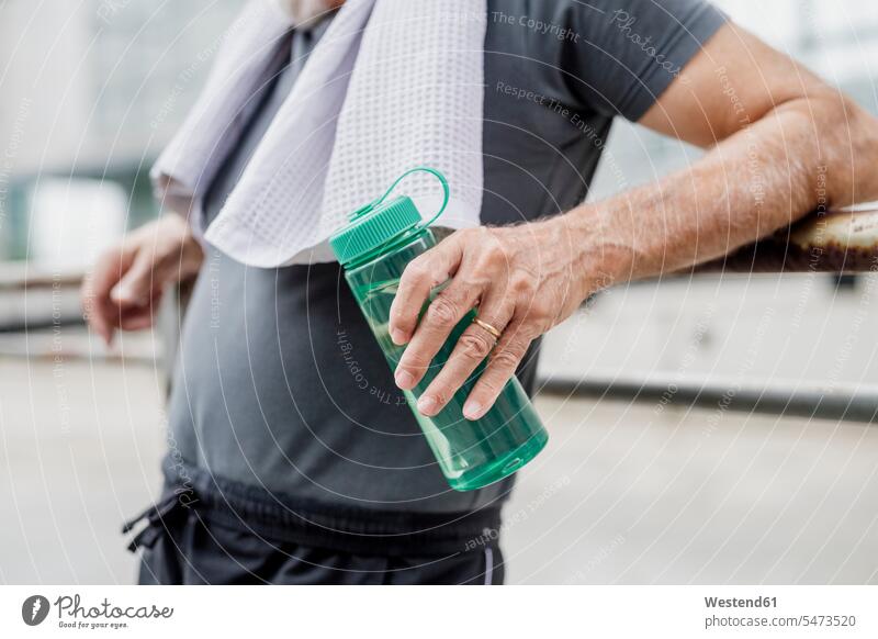 Close-up of senior man holding water bottle while standing in city color image colour image outdoors location shots outdoor shot outdoor shots day daylight shot