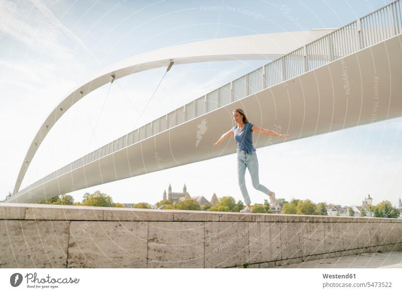 Netherlands, Maastricht, young woman balancing on a wall at a bridge balance walls bridges females women Balance Equilibrium balanced Adults grown-ups grownups