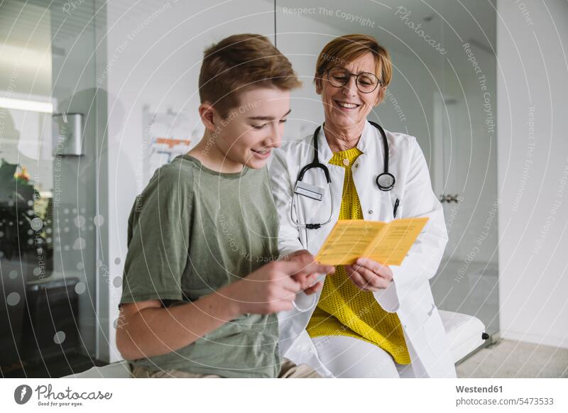 Doctor explaining vaccination to teenage boy in medical practice health healthcare Healthcare And Medicines medicine disease diseases ill illnesses sick