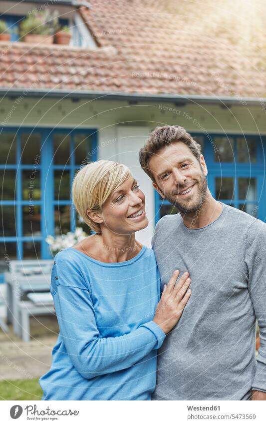 Portrait of smiling couple standing in front of their home smile portrait portraits twosomes partnership couples house houses people persons human being humans