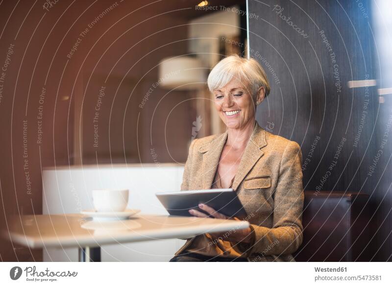 Smiling senior businesswoman using tablet in a cafe businesswomen business woman business women digitizer Tablet Computer Tablet PC Tablet Computers iPad