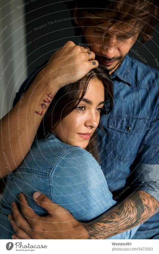 Tattooed man embracing girlfriend tattooed embrace Embracement hug hugging couple twosomes partnership couples tattoos people persons human being humans