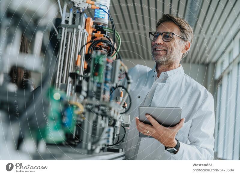 Smiling male scientist holding digital tablet examining machinery in laboratory color image colour image indoors indoor shot indoor shots interior interior view