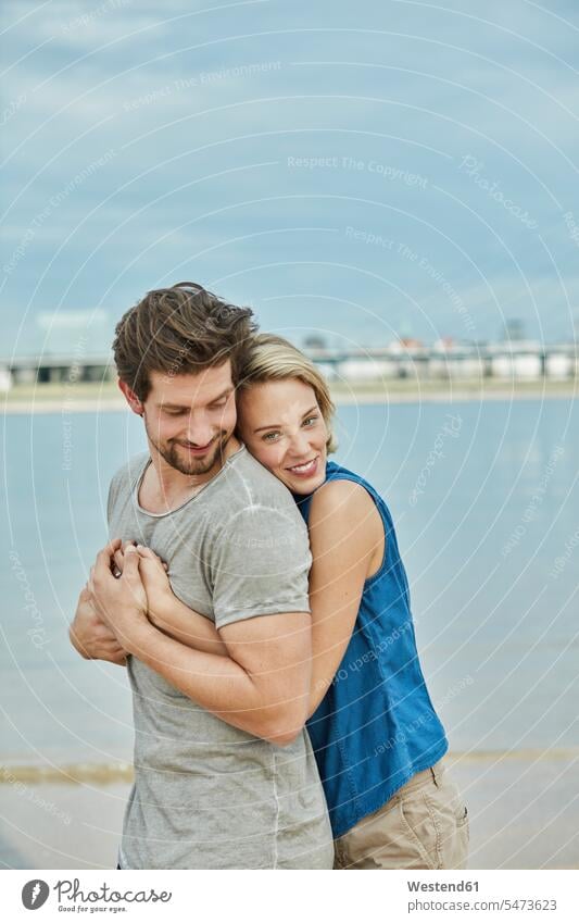 Happy young couple hugging at the riverbank River Rivers cuddling riverside twosomes partnership couples happiness happy water waters body of water water's edge