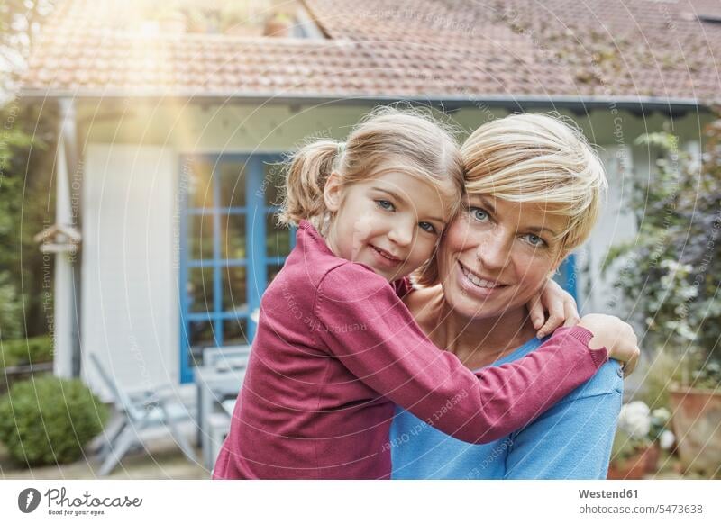 Portrait of smiling mother carrying daughter in front of their home smile house houses happiness happy portrait portraits mommy mothers ma mummy mama daughters