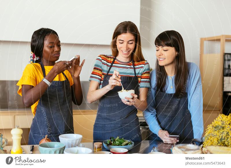 Friends taking smartphone pictures in a cooking workshop kitchen Smartphone iPhone Smartphones cooking class photographing female friends training course