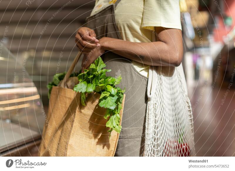 Mid section of woman buying groceries in a market hall human human being human beings humans person persons client clientele clients customers bags