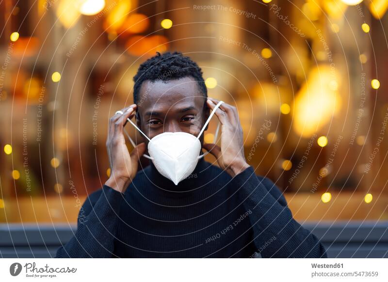 Young man wearing face mask while standing outdoors during Covid-19 color image colour image location shots outdoor shot outdoor shots day daylight shot