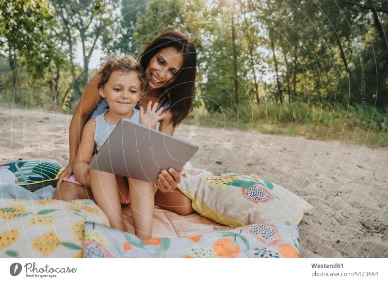 Mother and daughter making a video call at beach on sunny day color image colour image outdoors location shots outdoor shot outdoor shots daylight shot