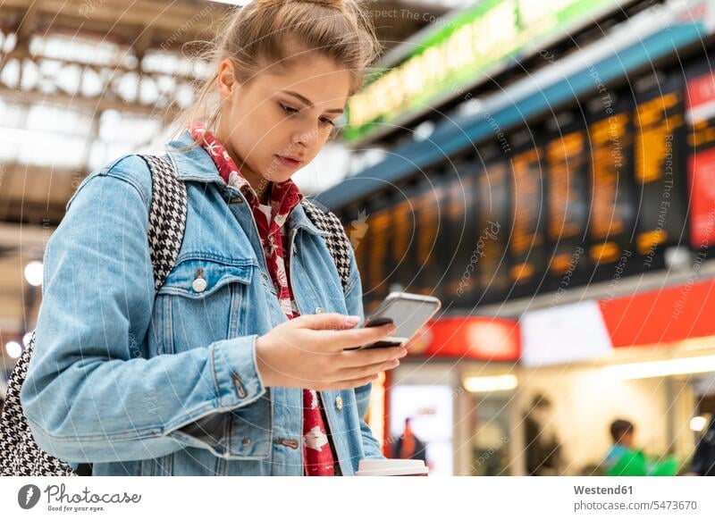 Young woman checking smartphone at the train station cities town towns urbanity city living Citylife Living in a City urban life human human being human beings