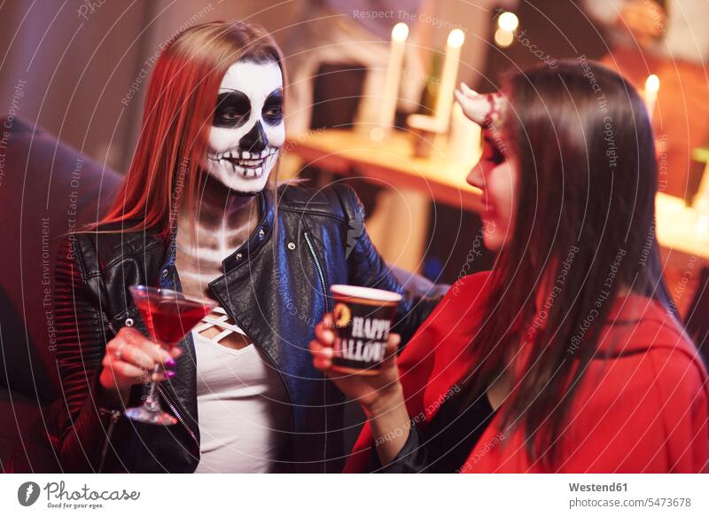 Women in creepy costume drinking at party friends talking speaking hooded Party Parties Halloween All Hallows' Eve celebrating celebrate partying friendship