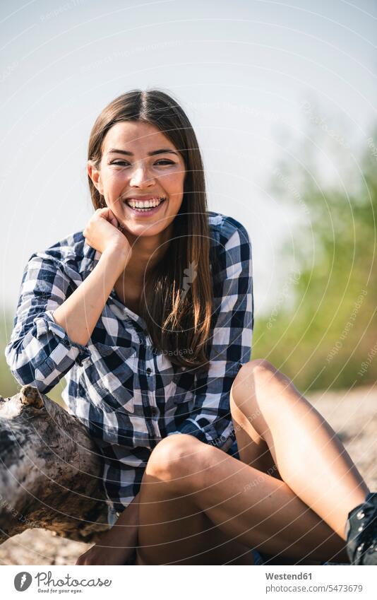 Portrait of happy young woman sitting outdoors happiness smiling smile Seated females women portrait portraits Adults grown-ups grownups adult people persons