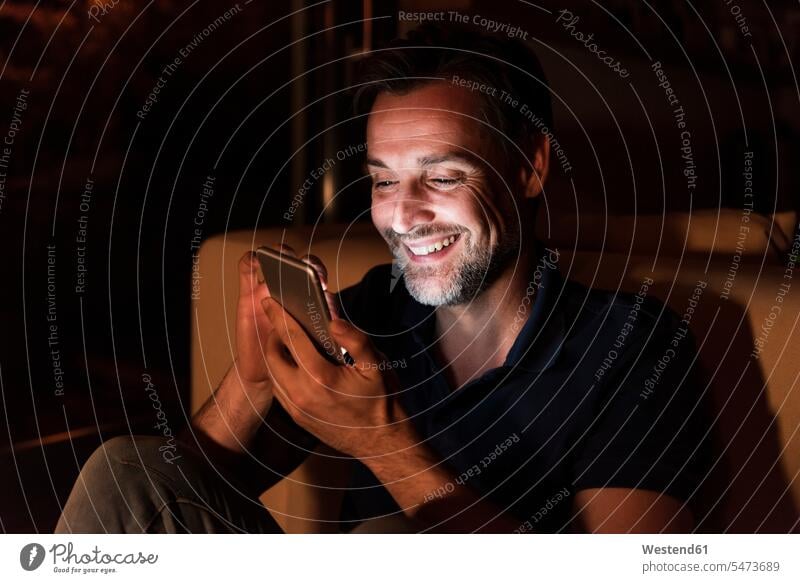 Portrait of happy mature man using cell phone at home happiness men males use Smartphone iPhone Smartphones portrait portraits Adults grown-ups grownups adult