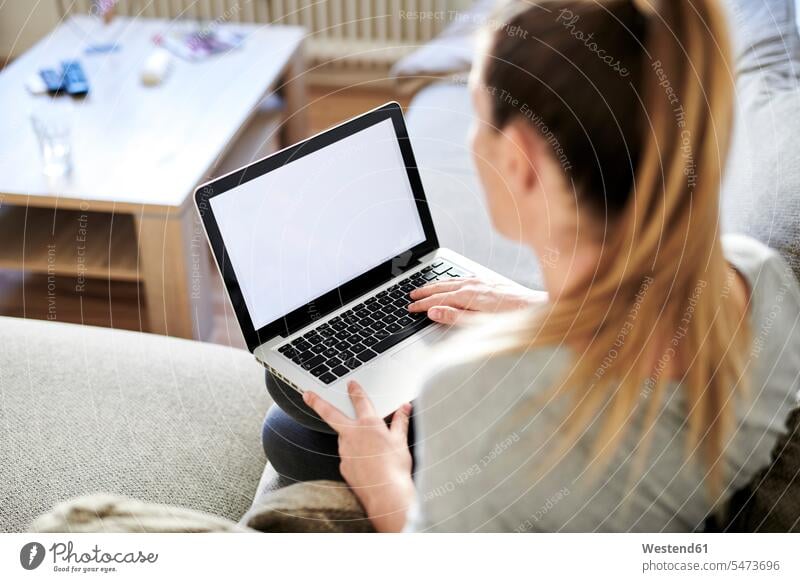 High angle view of woman using laptop while sitting on sofa at home color image colour image Germany elevated view High Angle View High Angle Shot