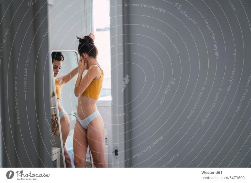 Young woman in underwear at home looking in mirror beautiful females women view seeing viewing mirrors Adults grown-ups grownups adult people persons