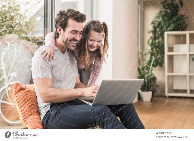 Young man and little girl surfing the net together Germany sitting on ground Sitting On The Floor Sitting On Floor using laptop using a laptop Using Laptops