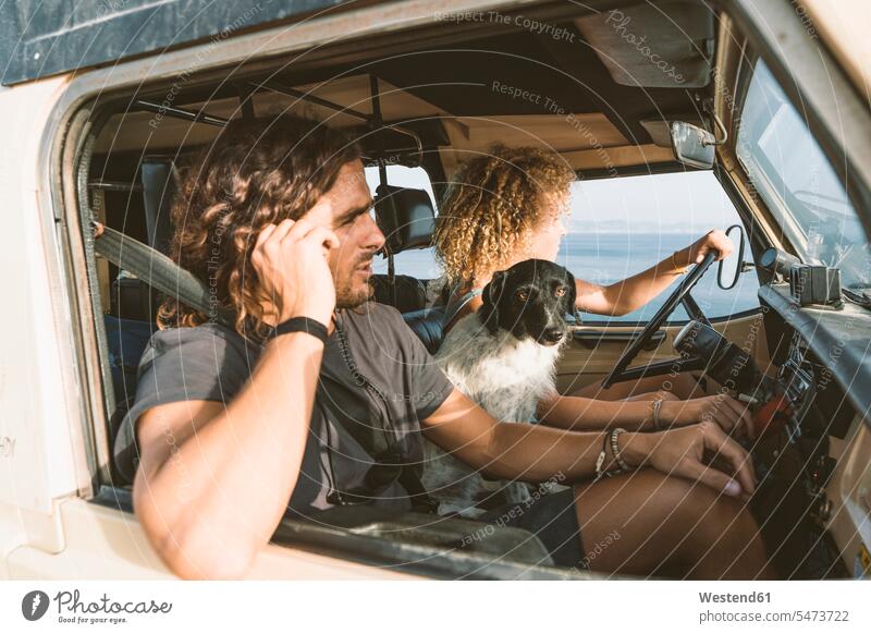 Young woman sitting by dog and man while driving car at beach animal themes animals creature creatures casual clothing casual wear leisure wear casual clothes