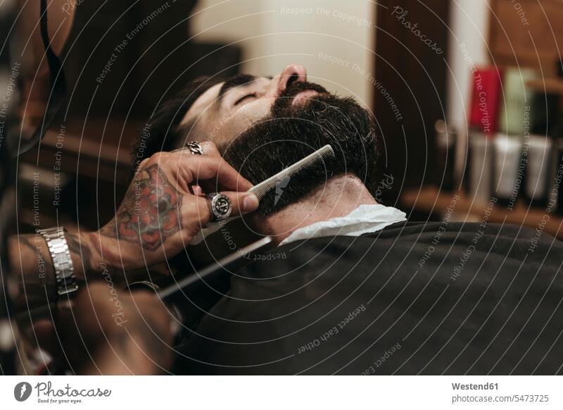 Barber combing client's beard at salon color image colour image indoors indoor shot indoor shots interior interior view Interiors day daylight shot
