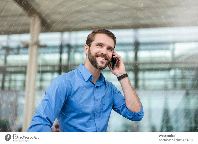 Smiling young businessman on cell phone outdoors smiling smile looking away look away on the phone call telephoning On The Telephone calling Businessman
