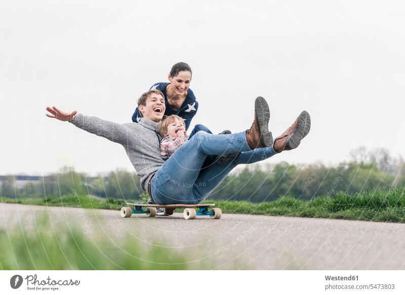 Father and son having fun, playing with skateboard outdoors balanced Equilibrium smile delight enjoyment Pleasant pleasure Cheerfulness exhilaration gaiety gay