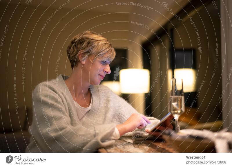 Blond woman working late while using digital tablet in illuminated living room color image colour image Germany Digital Tablet Tablet Computer Tablet PC