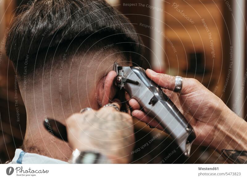 Barber's hands using electric razor on man at hair salon color image colour image indoors indoor shot indoor shots interior interior view Interiors day