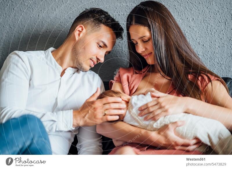 Father looking at baby boy being breastfed by mother at home color image colour image indoors indoor shot indoor shots interior interior view Interiors day