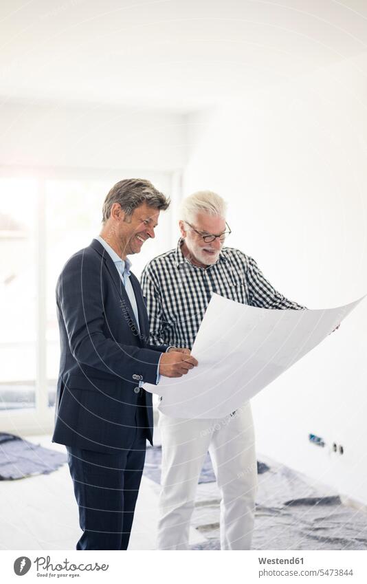Happy man in suit and senior man looking at blueprint talking speaking eyeing men males happiness happy Fullsuit suits full suit construction plan building plan