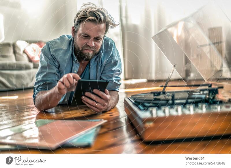 Man lying on the floor at home with tablet and record player human human being human beings humans person persons caucasian appearance caucasian ethnicity