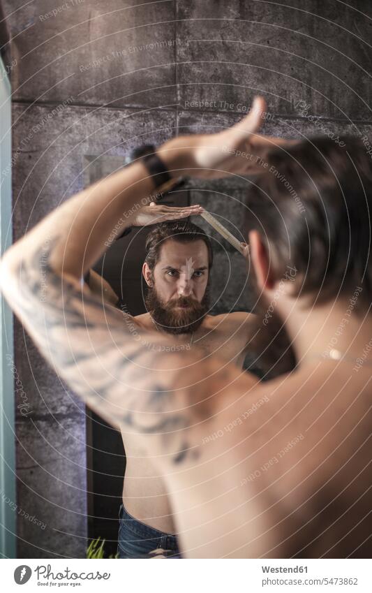 Portrait of bearded man looking at his mirror image while combing his hair men males reflexion reflection portrait portraits eyeing Adults grown-ups grownups