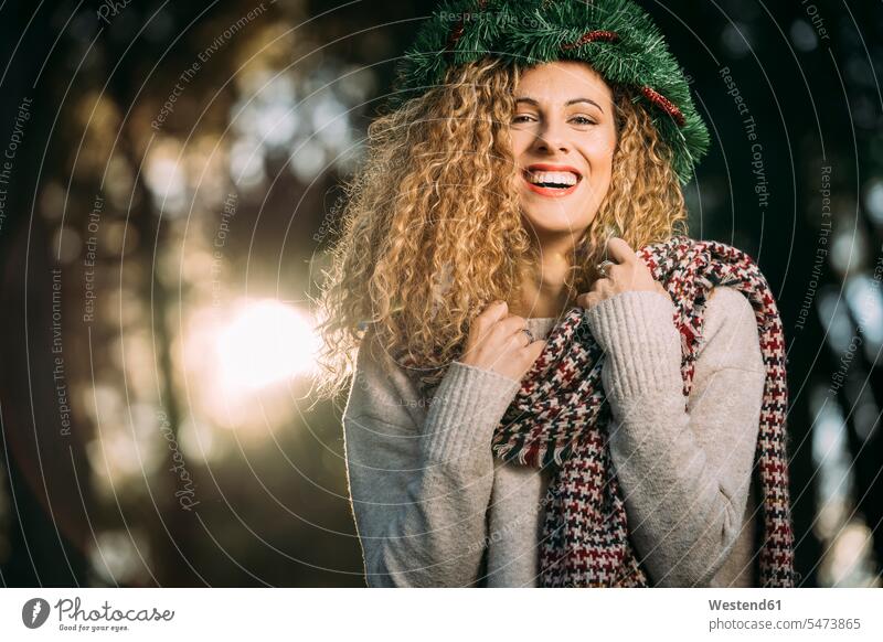 Portrait of laughing young woman wearing Christmas wreath on her head scarfs scarves in the evening delight enjoyment Pleasant pleasure Cheerfulness