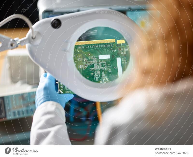 Female technician checking circuit board with magnifier female technician female technicians woman females women magnifying glass scrutiny scrutinizing