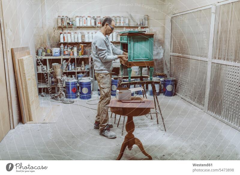 Manual worker working on antique furniture while standing at workshop color image colour image indoors indoor shot indoor shots interior interior view Interiors