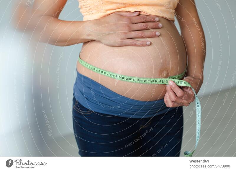 Young pregnant woman measuring her baby belly Measure Tape measuring tape measuring tapes tape measures hold happy at home Pregnant Woman developing